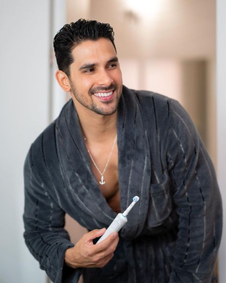 A man in his bathrobe with a toothbrush.